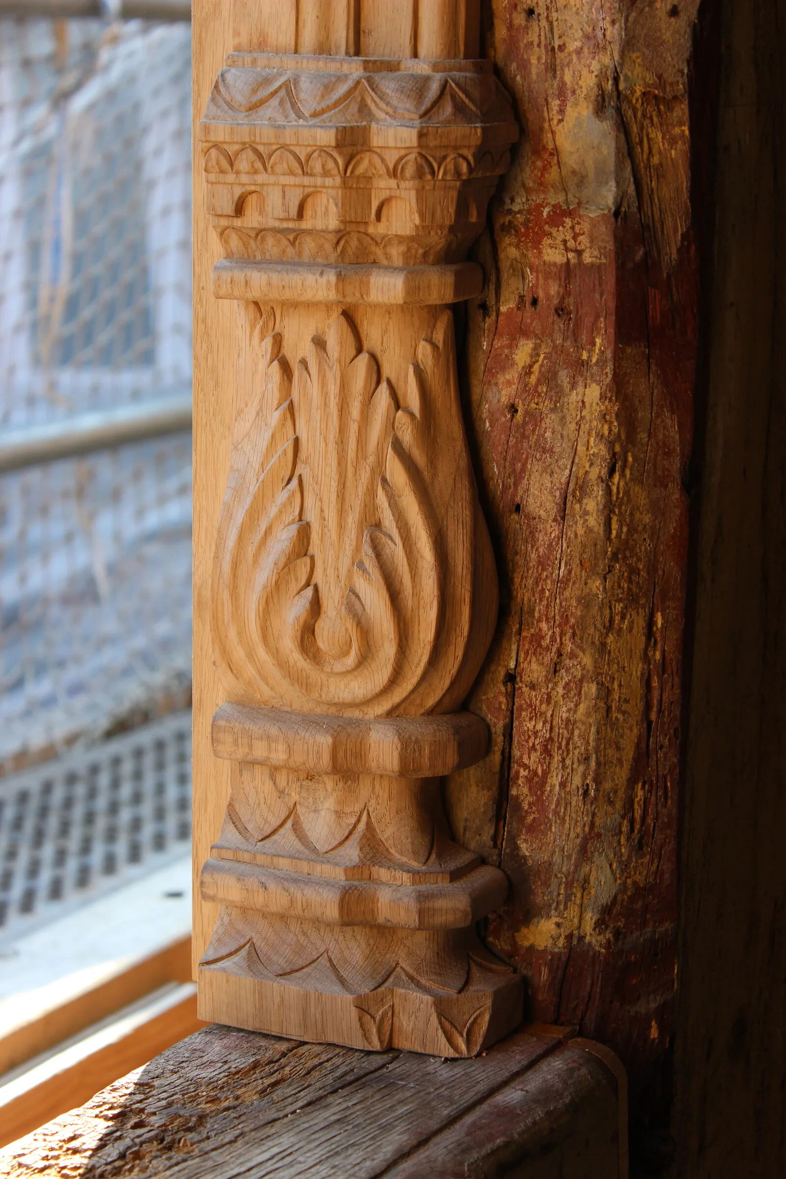 Neu geschnittener Eichen-Fensterpfosten mit Akanthusblatt, daneben das verwitterte historische Fachwerk